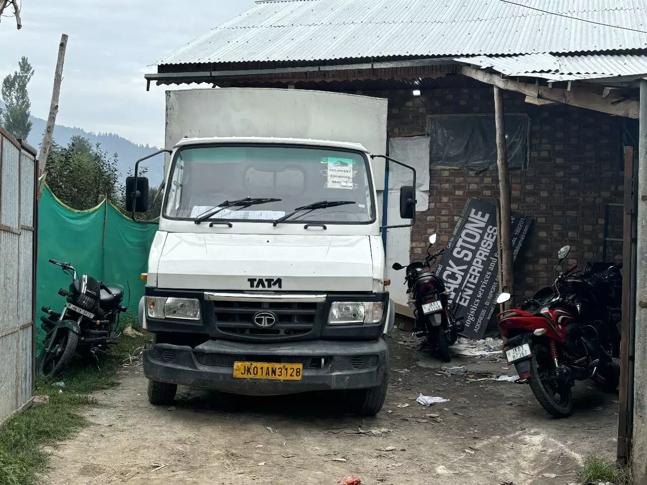 A truck is parked and being unloaded at the Delhivery warehouse in Achabal, Anantnag.